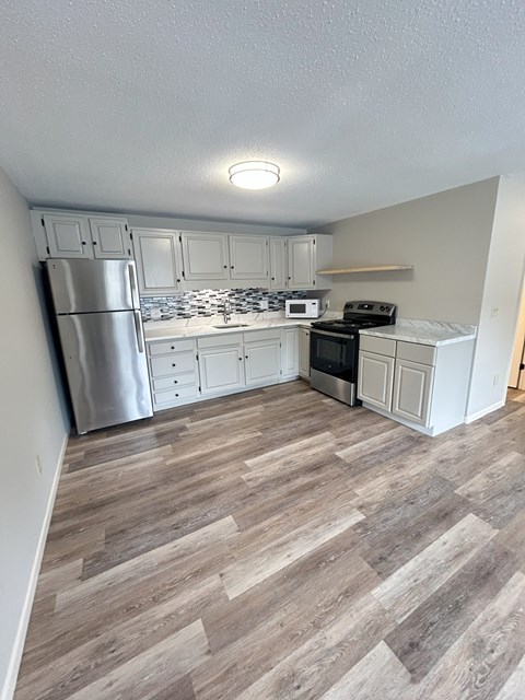 A kitchen with a refrigerator, microwave, oven, and cabinets. at Briarcliff at Quechee, Quechee, 05059